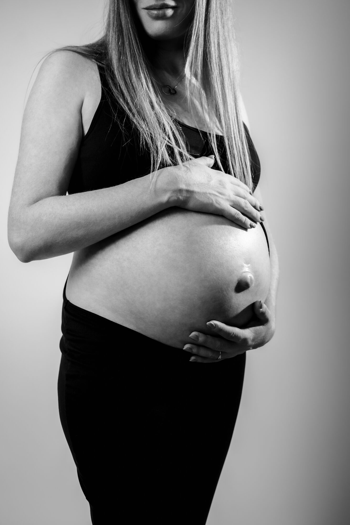 Mains sur un ventre de femme enceinte, noir et blanc